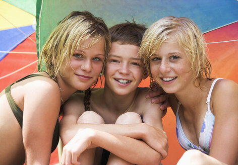Teenager-Mädchen (13-15) und Junge unter Sonnenschirm sitzend, Nahaufnahme, Porträt - WESTF01697
