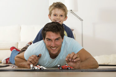 Vater und Sohn (6-7) spielen mit Spielzeugautos, lächelnd, Porträt - RDF00133