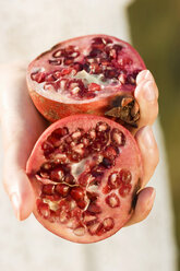 Woman holding pomegranate half's, close-up - NDF00052