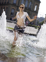 Teenage girl (16-17) splashing water in fountain - KMF00375