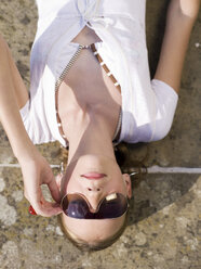 Jugendliches Mädchen (16-17) mit Sonnenbrille auf dem Rücken liegend, Nahaufnahme - KMF00374