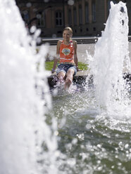 Teenager-Mädchen (16-17) sitzt am Brunnen - KMF00371