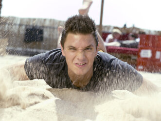 Young man throwing sand, blurred motion - KMF00358