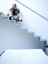 Junger Mann auf einer Treppe sitzend, tiefer Blickwinkel - KM00493