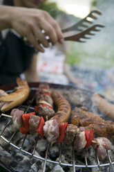 Meat and sausages on grill people in background - KMF00270