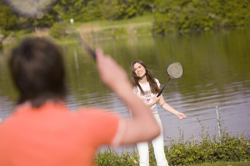 Young couple playing badminton, focus on woman - KMF00241