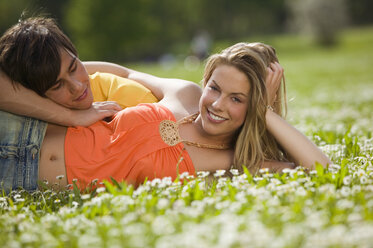 Young couple lying in meadow, smiling - KMF00213