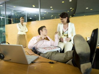 Couple having lunch in office, woman watching - WESTF02715