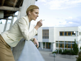 Businesswoman smoking on balcony - WESTF02700