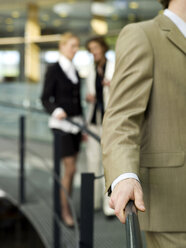 Women talking behind back of young businessman - WESTF02642