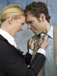 Businesswoman grabbing man by tie, shouting, side view, close-up - WESTF02620