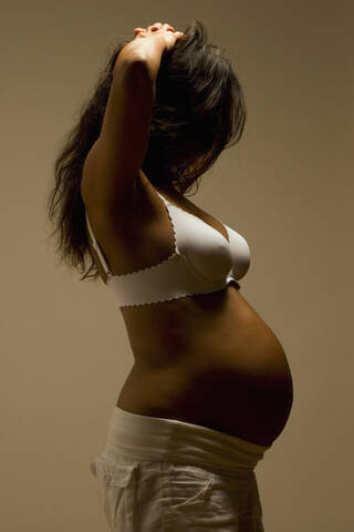 Pregnant woman, hands in hair, side view, lizenzfreies Stockfoto