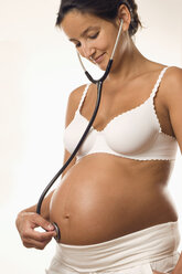 Pregnant woman holding stethoscope on belly, close-up - LDF00280