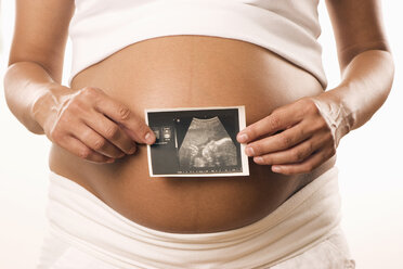 Pregnant woman holding ultrasonic picture, midsection, close-up - LDF00274