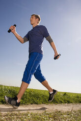Junger Mann joggt, trägt Hanteln - WESTF02598