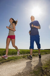 Junges Paar joggt, Mann trägt Hanteln - WESTF02596