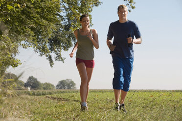 Young couple jogging in field - WESTF02589