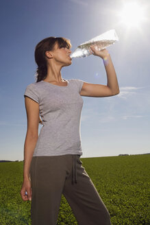 Junge Frau trinkt aus einer Wasserflasche - WESTF02548