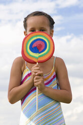 Girl (7-9) holding giant lollipop in front of face, close-up, portrait - LDF00331