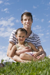 Father sitting with daughter (7-9) in meadow, portrait, close-up - LDF00329