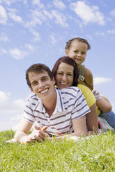 Parents with daughter (7-9) lying on grass, portrait, close-up - LDF00327