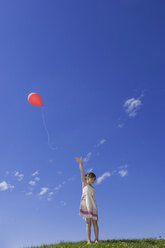 Girl (7-9) standing in meadow, releasing balloon - LDF00315