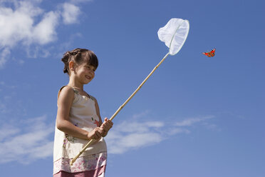 Girl (7-9) holding net, trying to catch butterfly - LDF00304