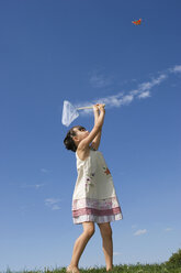 Girl (7-9) holding net, trying to catch butterfly - LDF00303