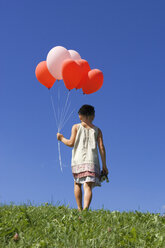 Girl (7-9) holding bunch of ballons, rear view - LDF00292