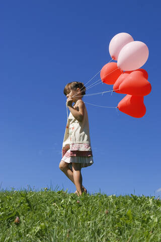 Girl (7-9) holding bunch of ballons, side view stock photo