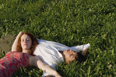 Woman lying with head on man`s belly in meadow - LDF00247