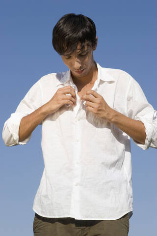 Junger Mann, der ein Hemd anzieht, lizenzfreies Stockfoto