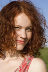 Young woman standing in meadow, smiling, portrait - LDF00234