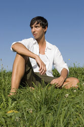 Young man sitting in meadow - LDF00224
