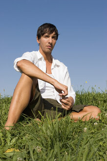 Young man sitting in meadow - LDF00223