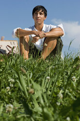 Young man sitting in meadow - LDF00209