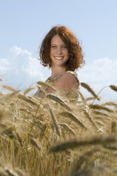 Young woman standing in cornfield, smiling - LDF00187