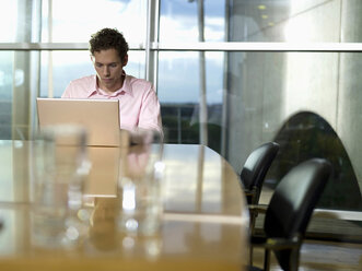Junger Mann im Büro, arbeitet am Laptop - WESTF02880