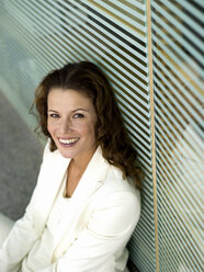 Businesswoman sitting on floor, smiling, elevated view, portrait - WESTF02760