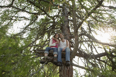 Junges Paar auf einem Baumhaus sitzend, sich umarmend - BABF00222