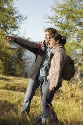 Young couple walking in meadow, man pointing - BABF00103