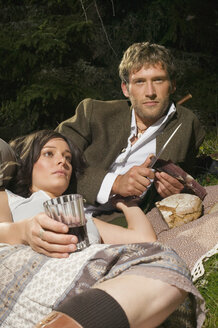 Junges Paar liegt auf einer Wiese und macht ein Picknick - BABF00074