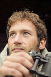 Young man holding binocular, close-up - BABF00007