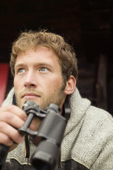 Young man holding binocular, close-up - BABF00006