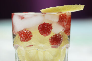 Raspberries, lemon slices and ice cubes in water glass, close-up - ASF02616