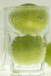 Zwei Limettenfrüchte in einem Glas Wasser - ASF02587