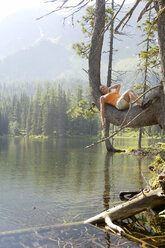 Young woman lying on branch of tree - HHF00800