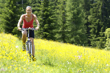 Junge Frau beim Mountainbiken im Feld - HHF00779