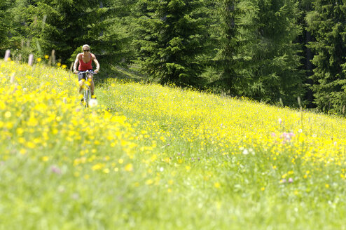 Junge Frau beim Mountainbiken im Feld - HHF00778