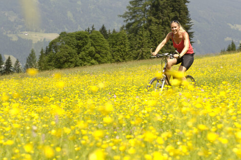 Junge Frau beim Mountainbiken im Feld - HHF00774